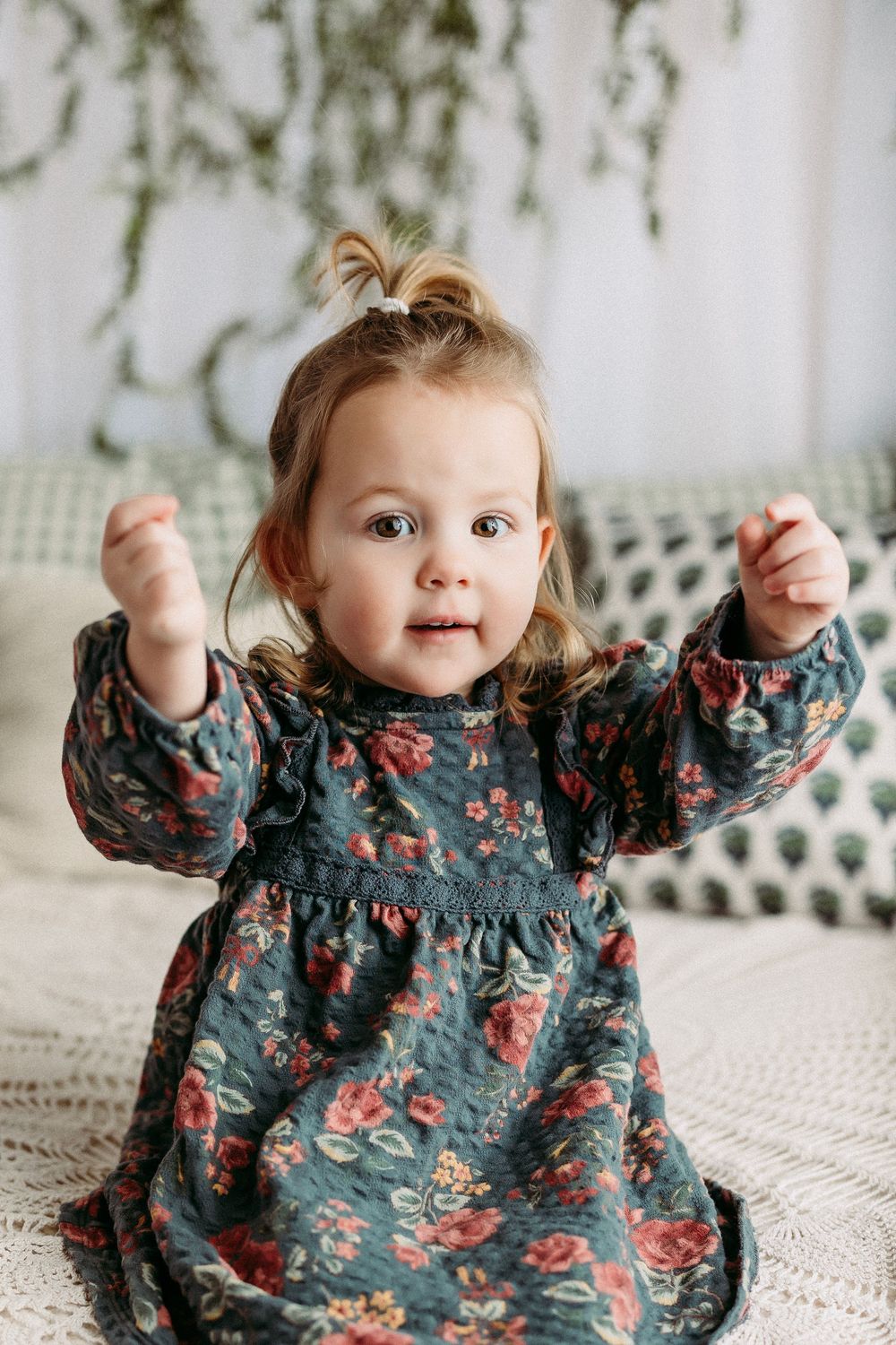 A series of photos showing a baby in a navy floral dress sitting on a white textured surface.