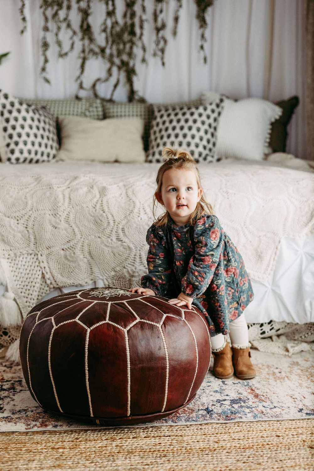 Brown leather pouf ottoman on jute rug with white couch and decorative pillows in cozy living room setting.