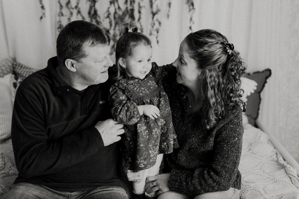 A family shares an intimate moment together while sitting on a couch in black and white.