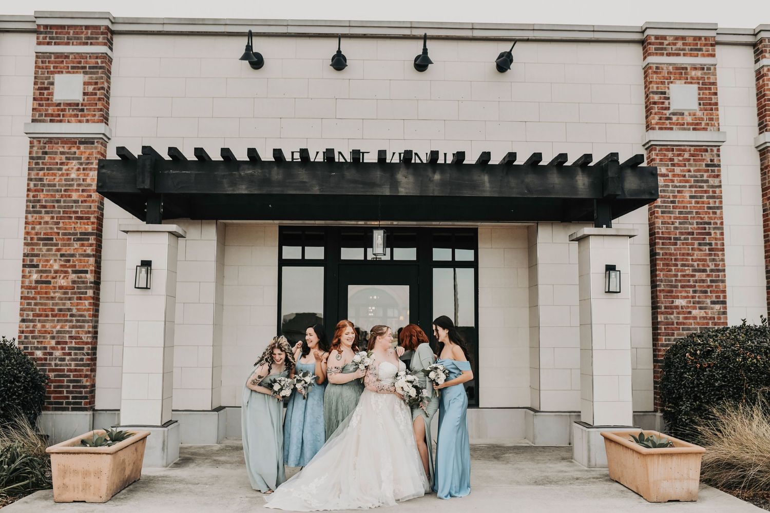Bridal party posing outdoors in winter light with modern greenery and white florals
