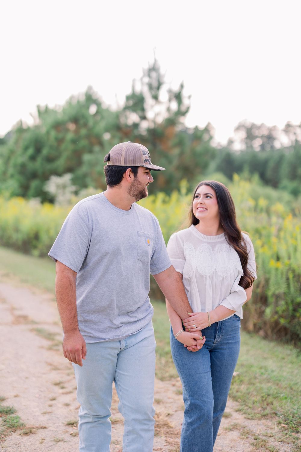 A couple sharing a loving glance while walking along a countryside path.