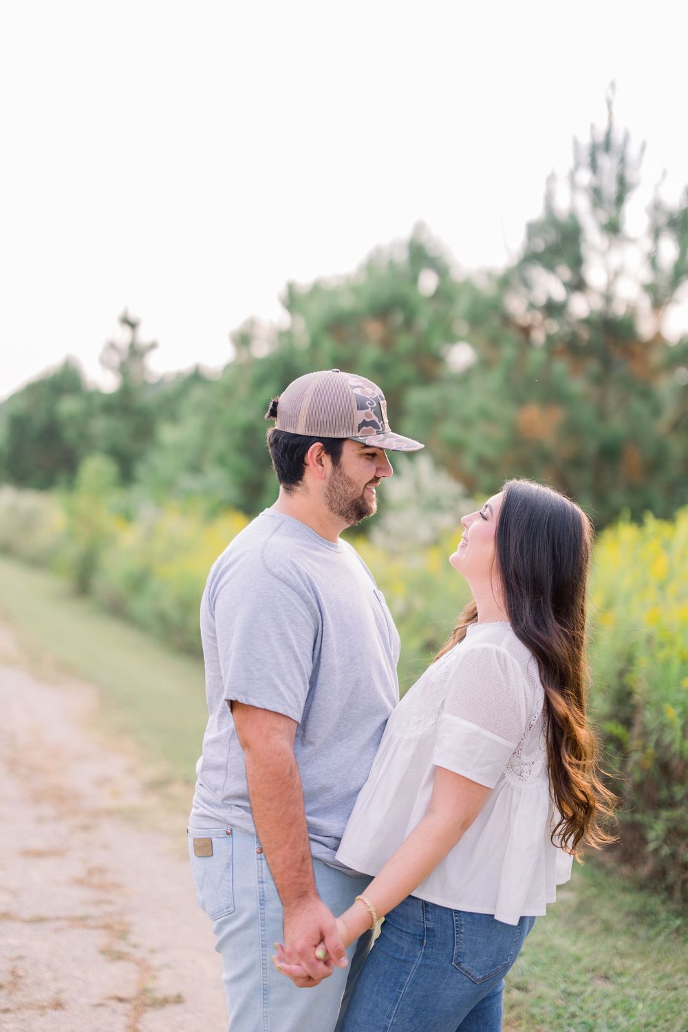 Couple holding hands and walking along a scenic nature path with yellow wildflowers in bloom.