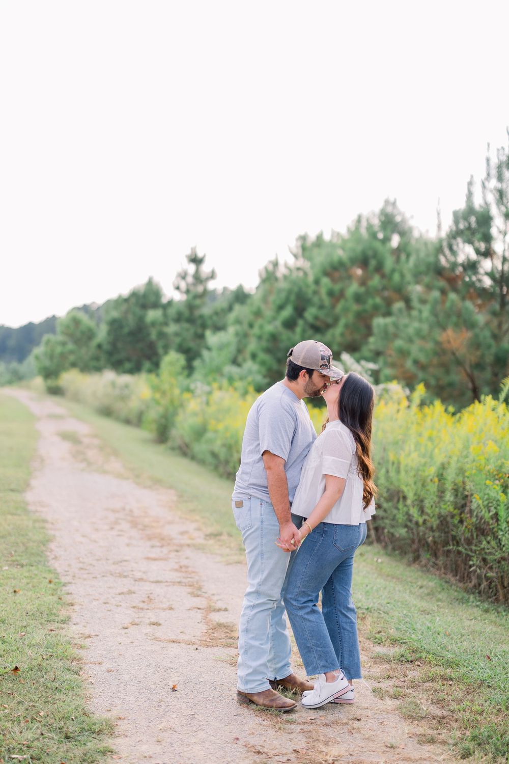 Couple sharing intimate moments while walking along a countryside path with wildflowers.