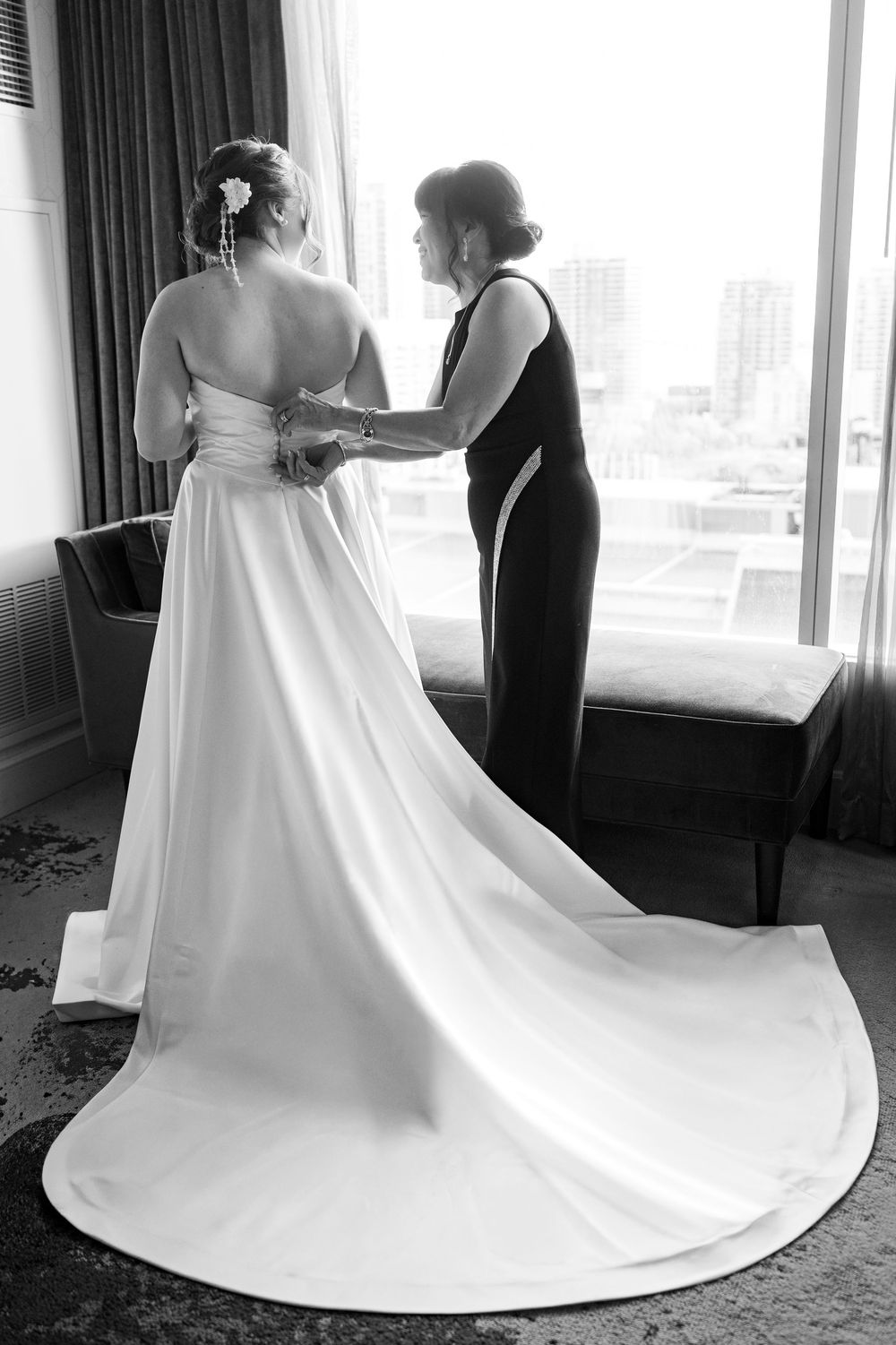 A white wedding dress with a long flowing train shown from multiple angles in a hotel room setting.