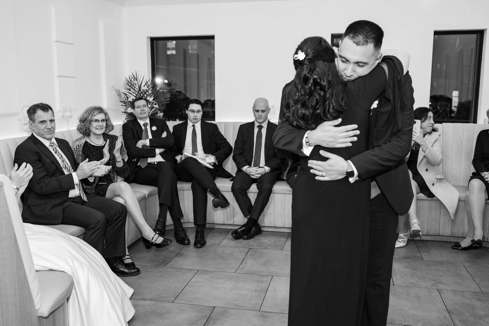 A couple shares a romantic dance together during a wedding reception with other guests visible in the background.