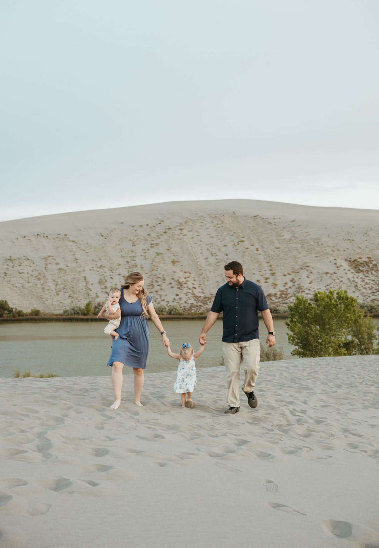 A young family sitting and playing at the Sand dunes in Idaho while taking family pictures.