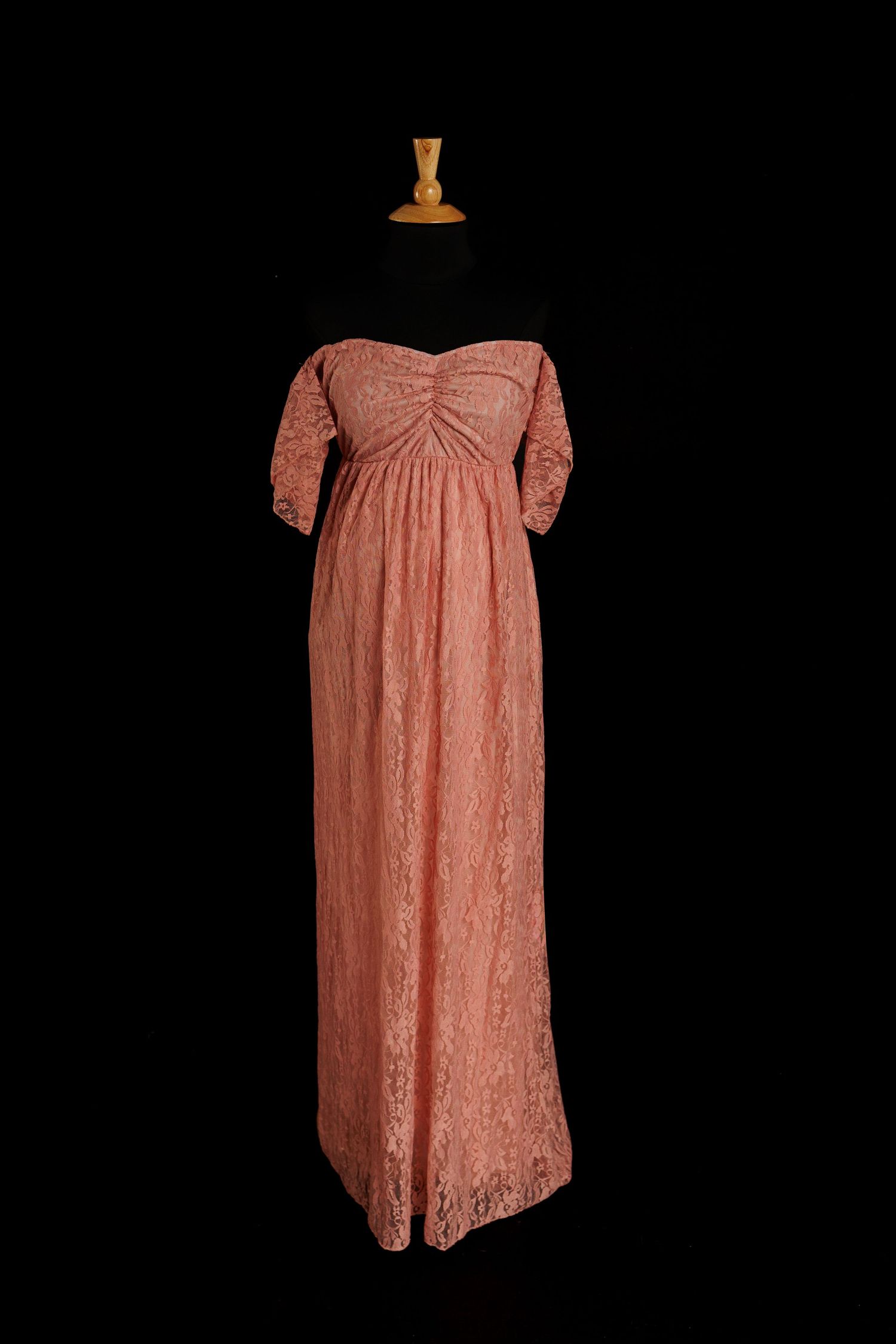 Blush pink lace maternity gown with sweetheart neckline, short sleeves, and floor-length skirt on mannequin