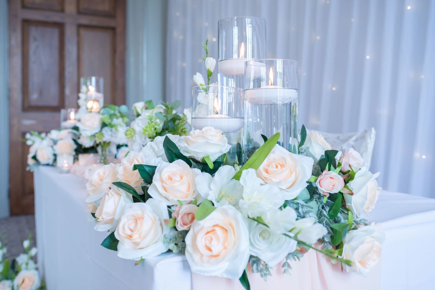 Elegant wedding reception table decorated with peach roses and white floral arrangements in a luxurious venue.