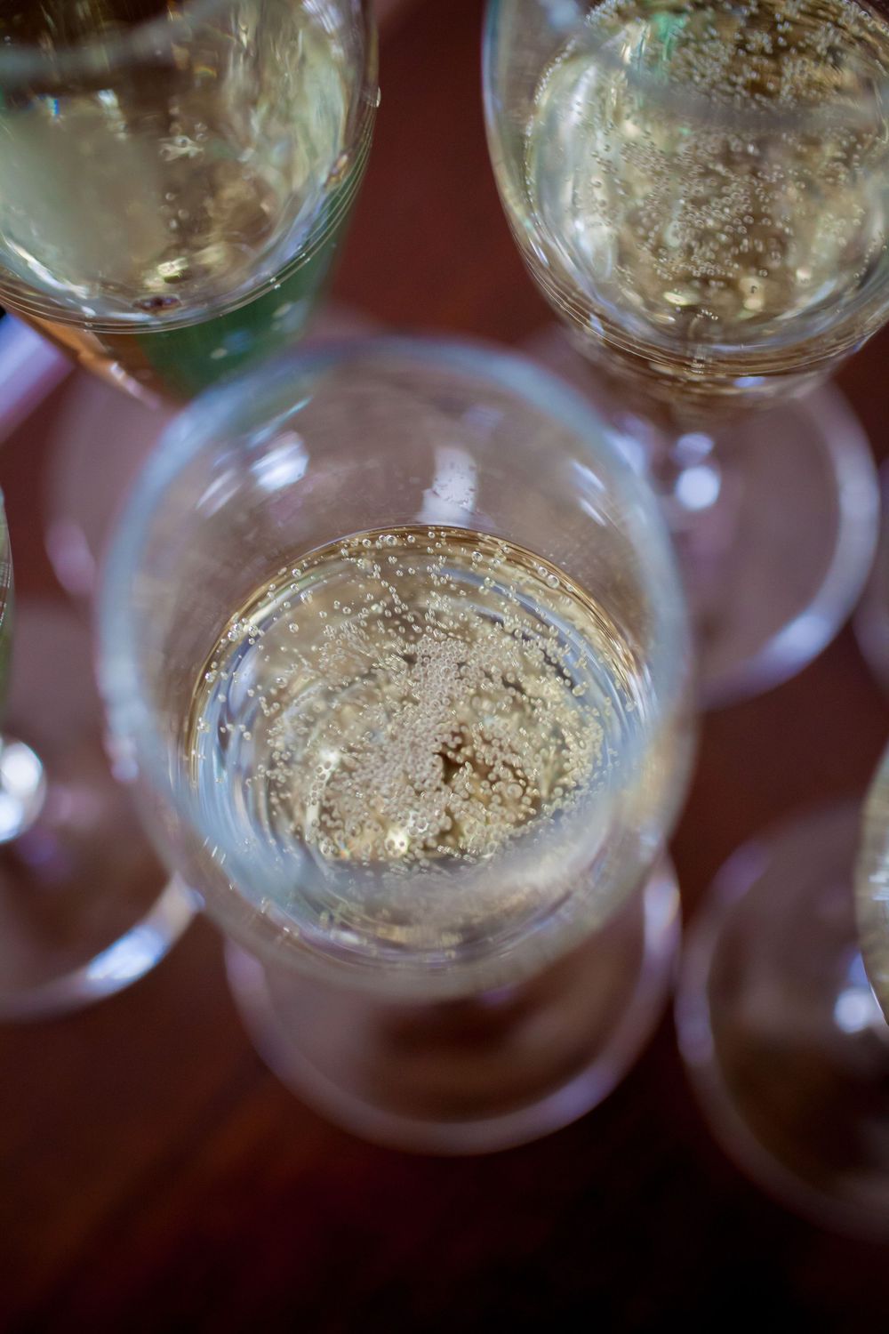Overhead view of empty champagne glasses with residual bubbles and condensation on a dark surface.