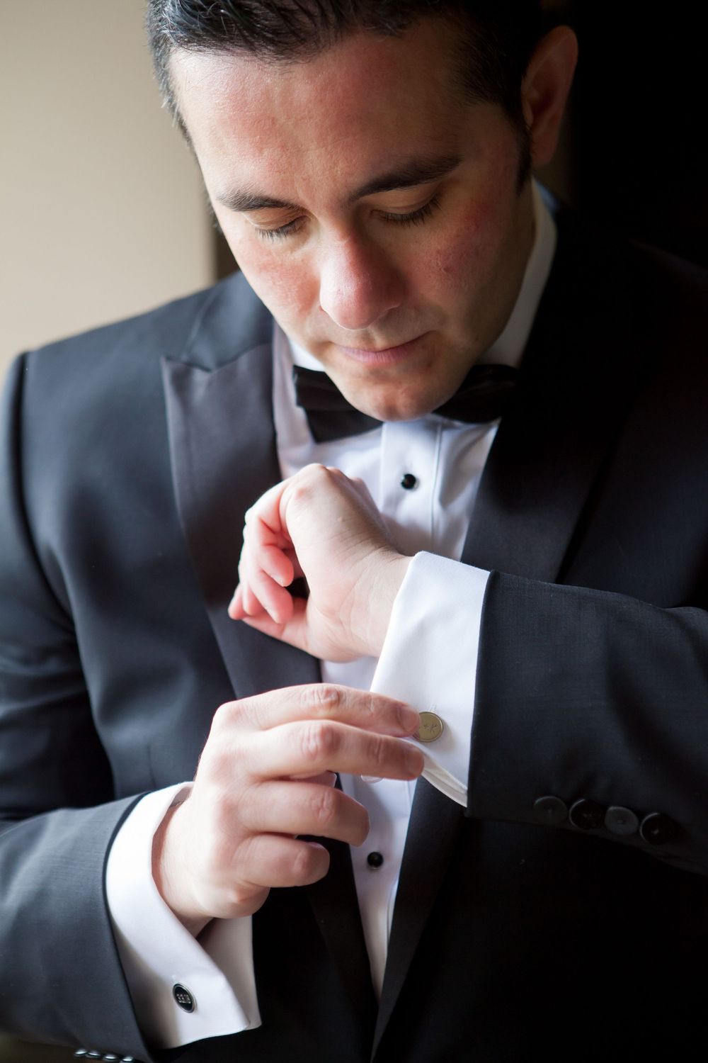 Close-up sequence of someone in a tuxedo adjusting their white cuff links against a dark background.