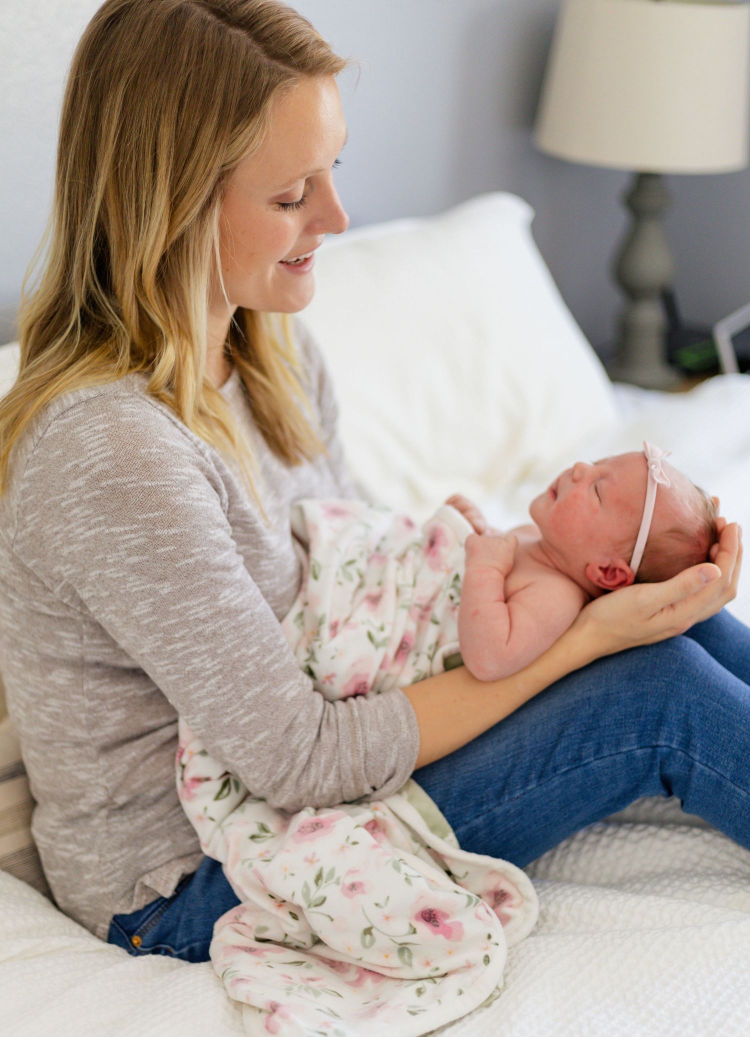 A tender moment between parent and newborn baby lying on white bedding.
