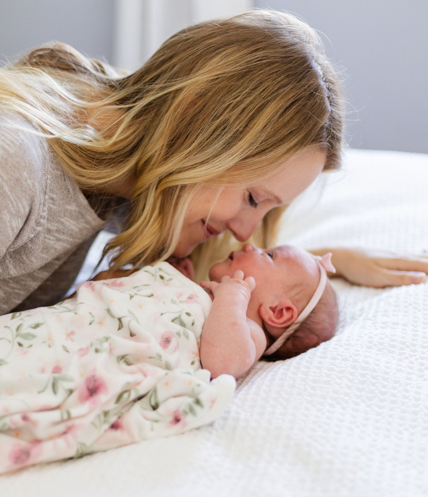 Intimate bonding moment with newborn baby on white sheets.