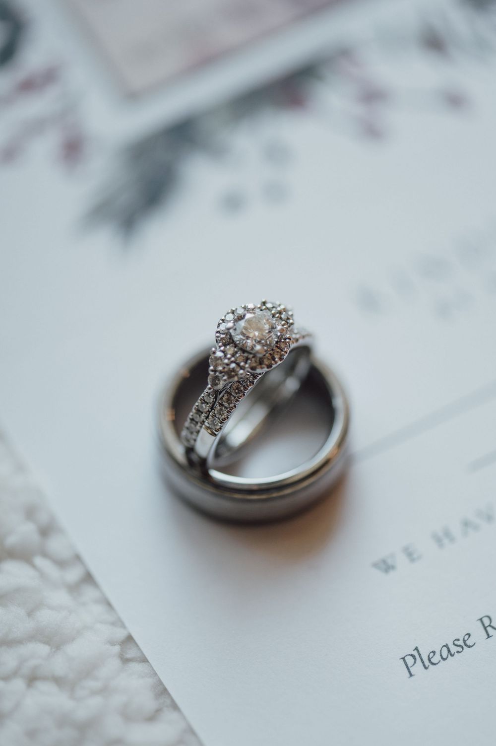 Diamond engagement ring and wedding band set photographed on white paper with elegant details.