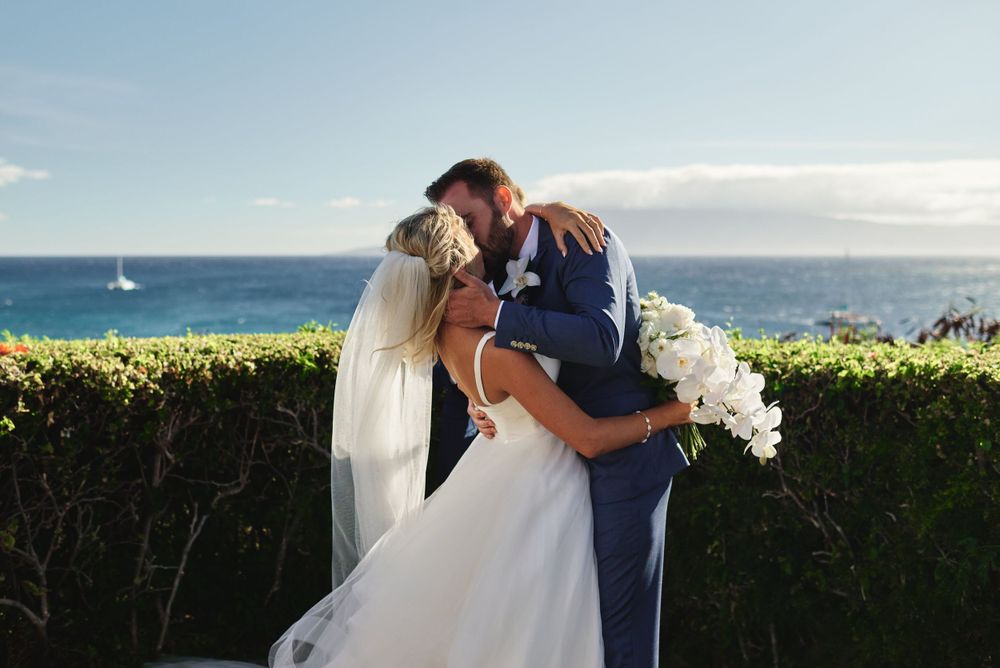 Newlyweds share romantic moments against a stunning ocean backdrop.