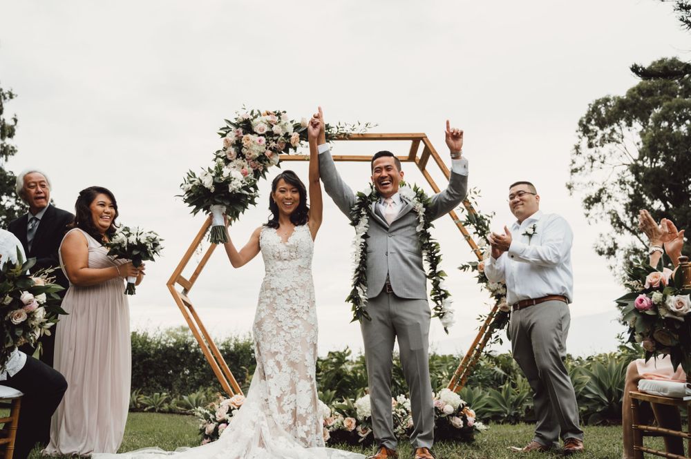 Outdoor wedding ceremony with wooden hexagon arch and floral decorations.