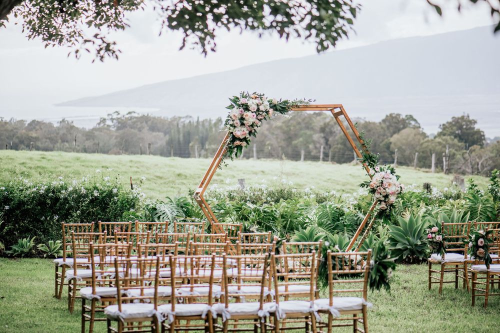 Outdoor wedding venue setup with wooden chairs arranged in rows on a grassy field.