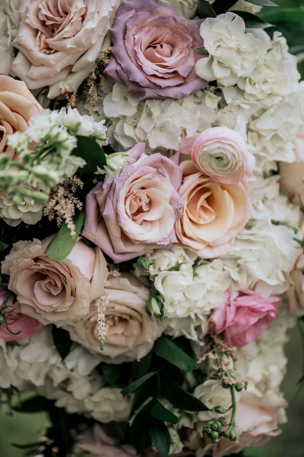 Elegant wedding bouquet featuring blush pink roses, white hydrangeas, and soft pastel flowers with greenery.
