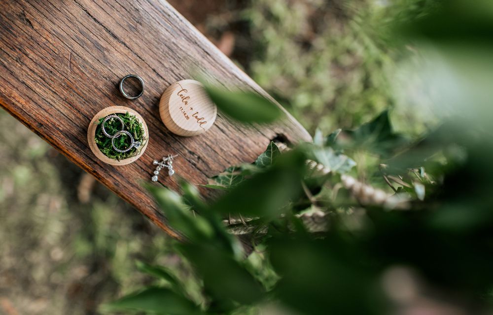 Wedding rings and delicate details displayed on rustic wooden surfaces with natural lighting.