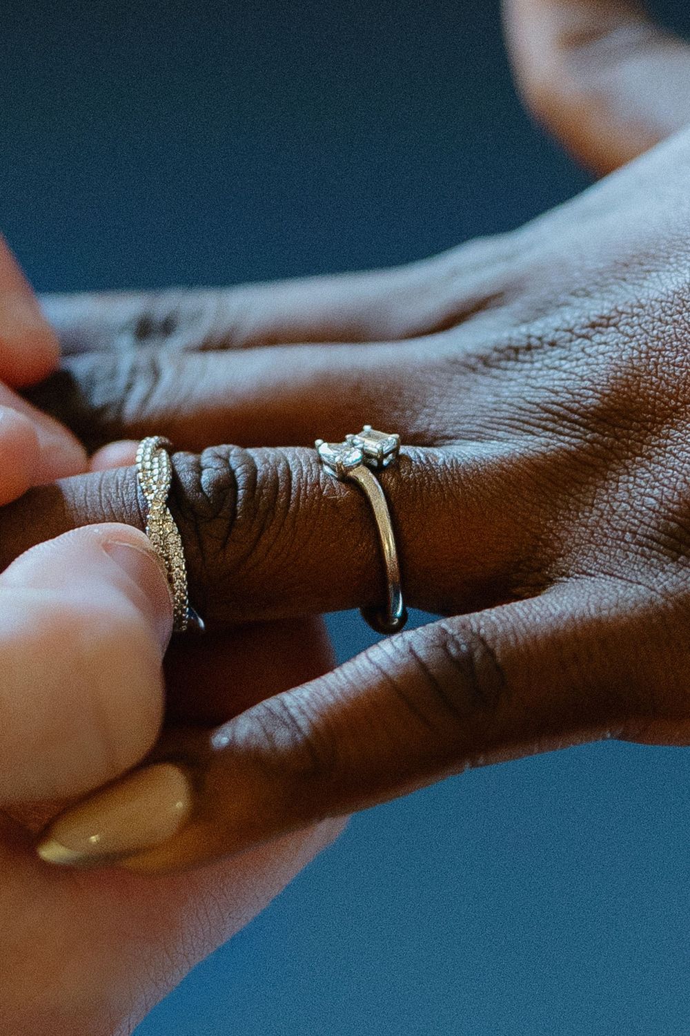 Close-up view of hands exchanging rings during an intimate wedding ceremony in soft lighting.