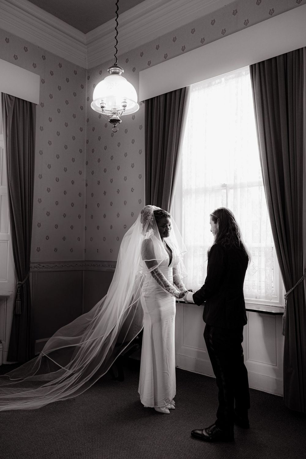 Black and white photo series showing silhouettes of a bride in flowing veil with another figure by window.