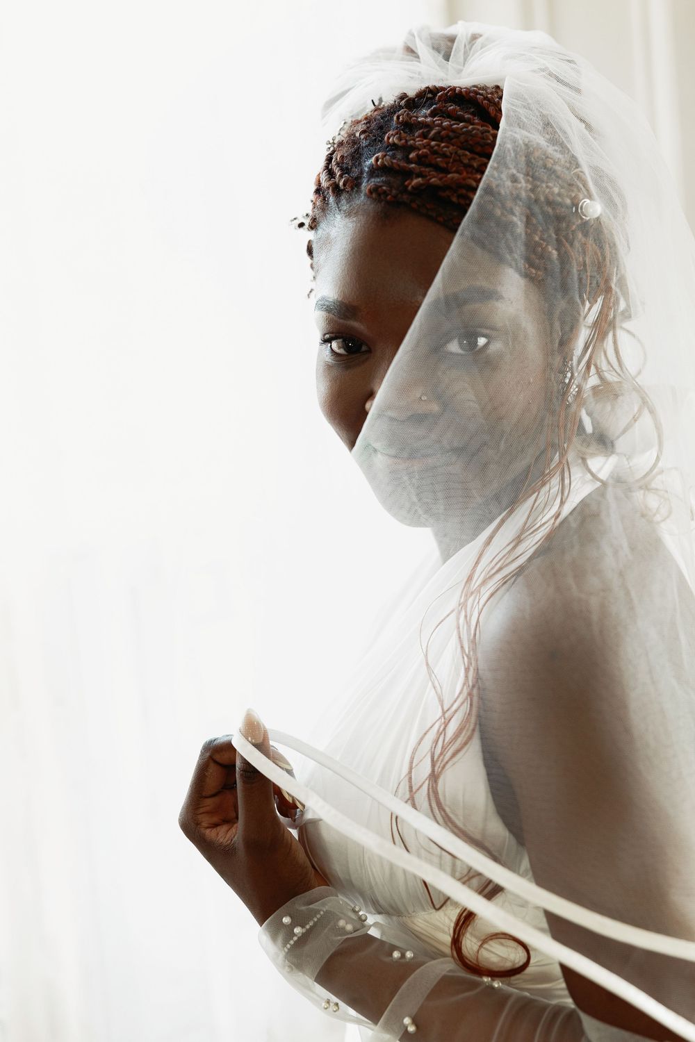 A bride wearing a delicate white veil gazes upward in a soft, ethereal bridal portrait.