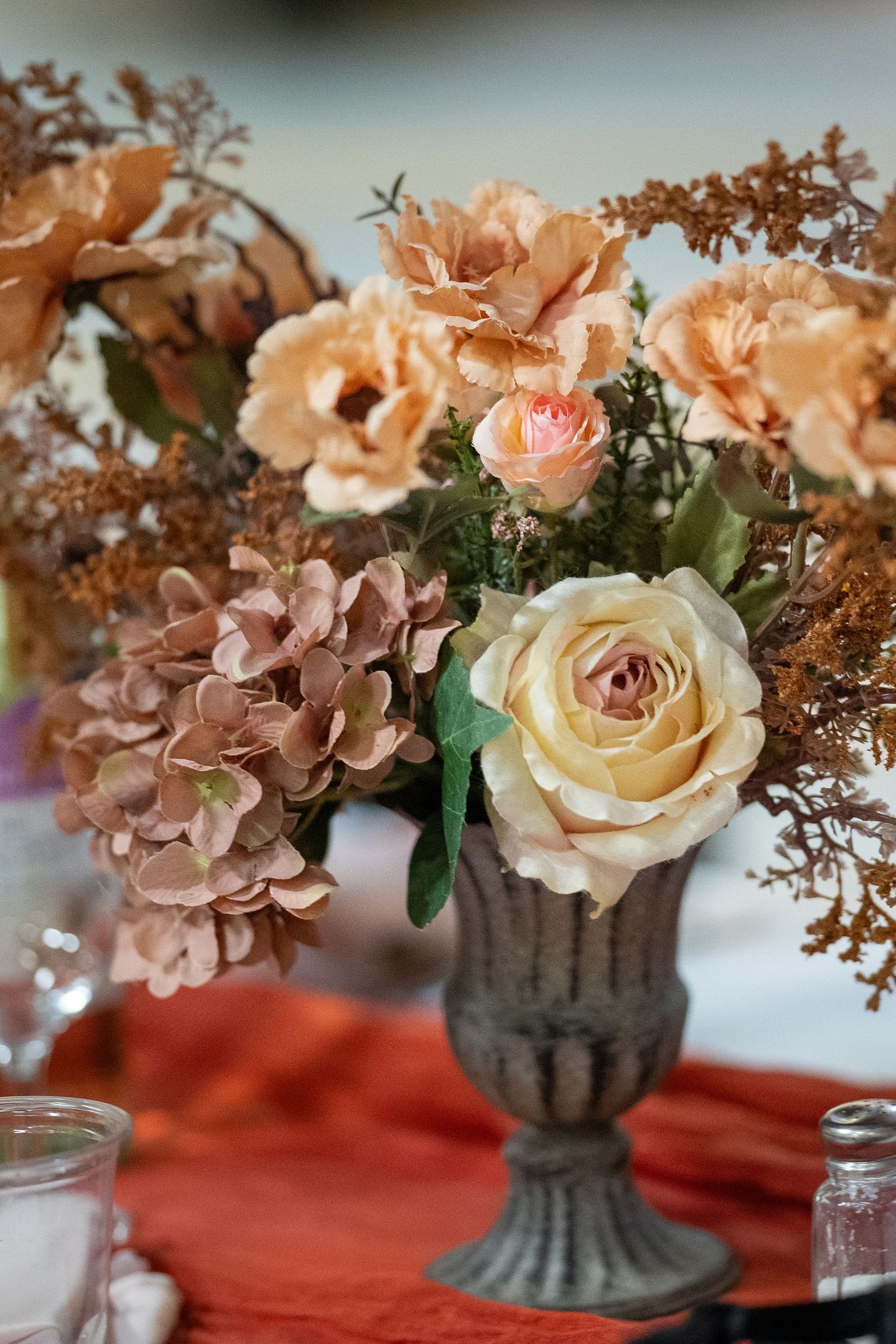 A couple shares their first dance at their wedding reception with autumn floral decor and twinkle lights in the background.