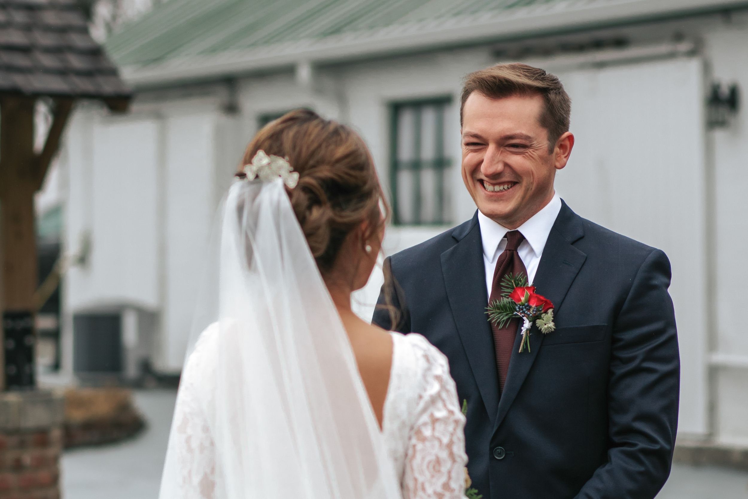 A joyful moment between a couple on their wedding day, with the bride in a lace gown and veil.