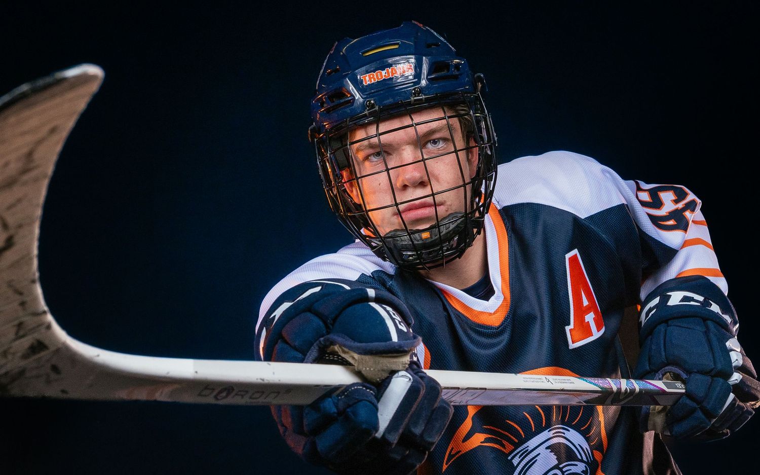 Hershey Trojans high school hockey player portrait in blue jersey, dramatic lighting, Central Pennsylvania, by SportsFox Photography,