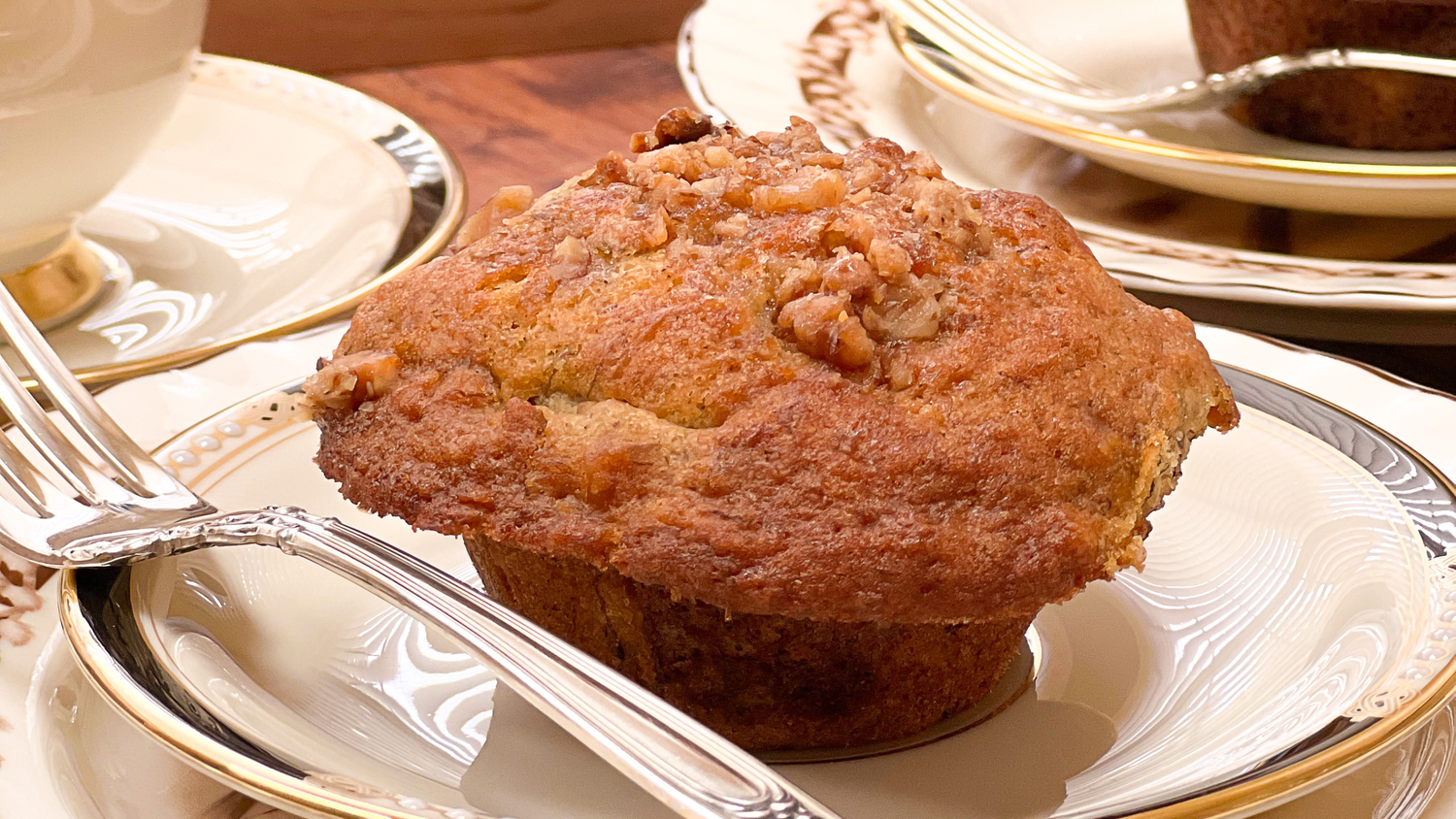 Freshly baked chocolate chip banana muffins cooling on white plates at a table setting.