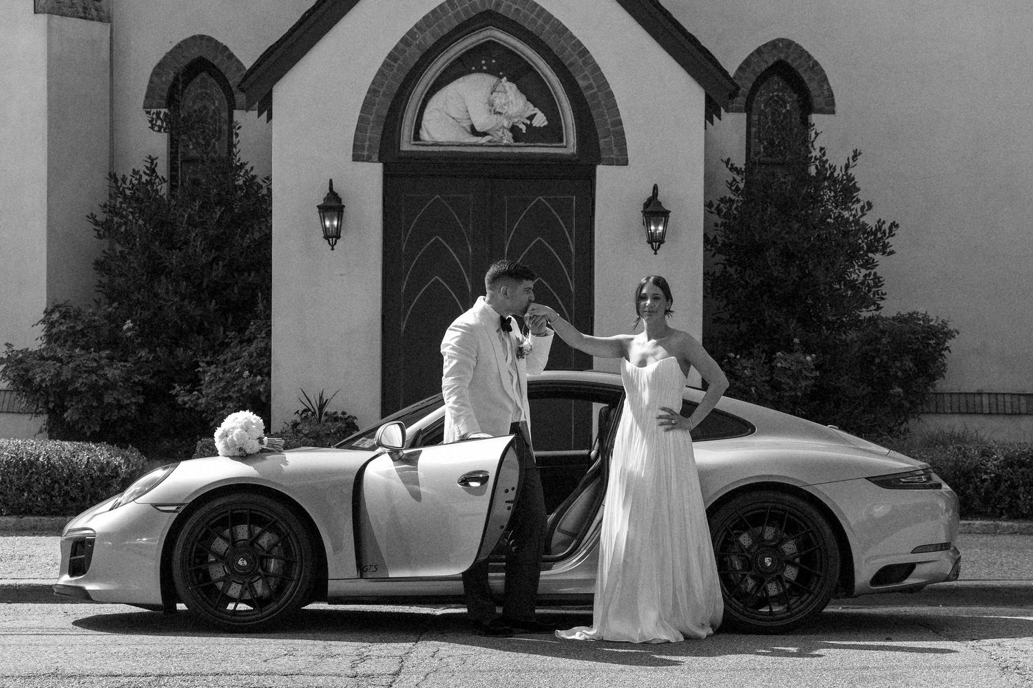 Classic wedding photography sequence with vintage car and church architecture in black and white.