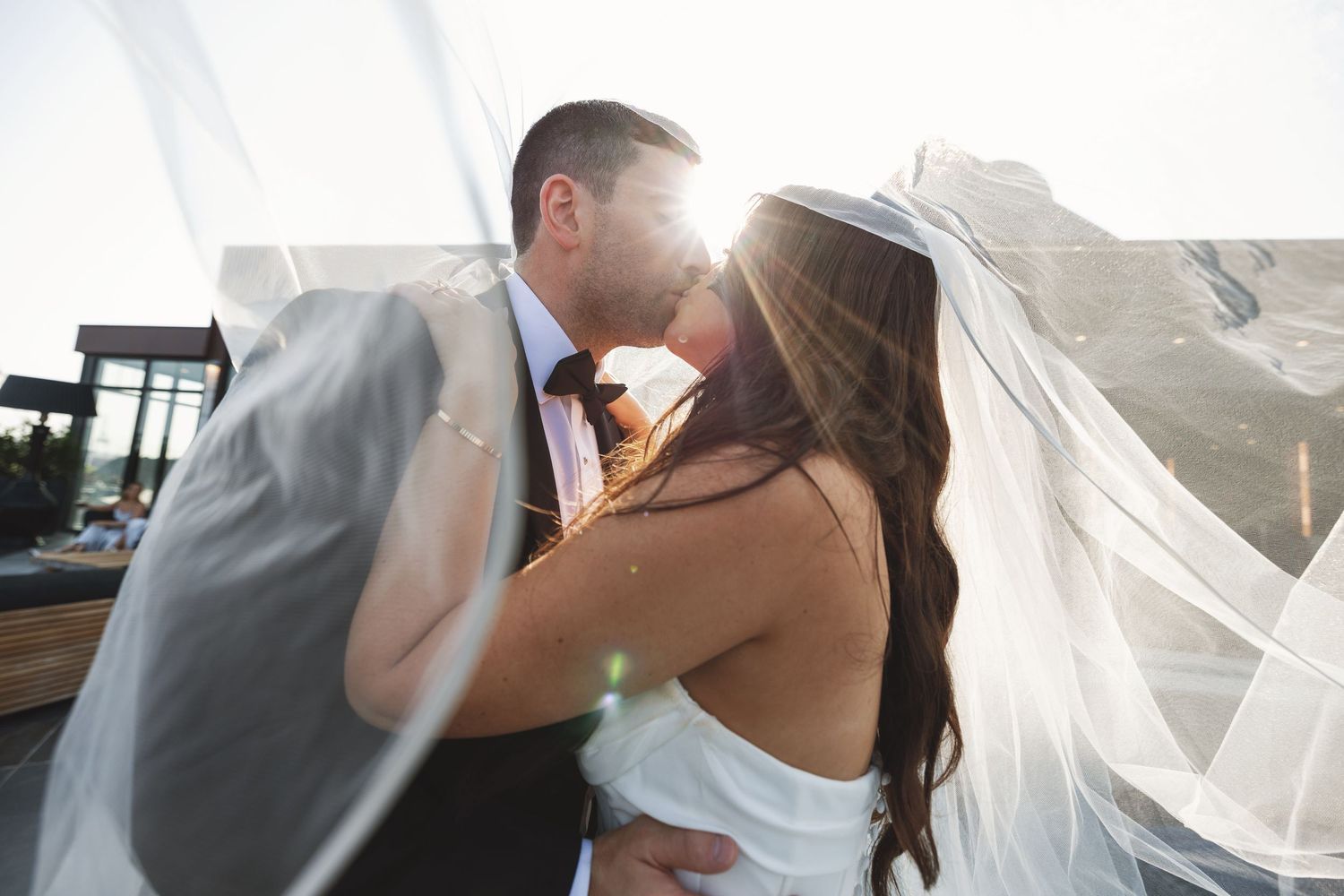 A sunlit wedding photo with the bride's veil flowing in the breeze.