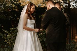 A couple shares an intimate moment during their outdoor wedding ceremony surrounded by lush greenery and natural light.