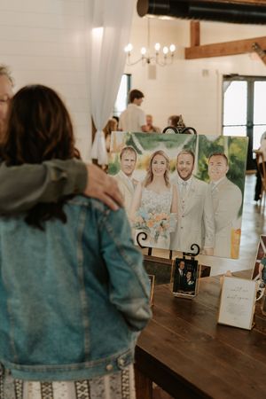 A wedding photo display on a wooden table shows a framed portrait with decorative stands and candles.