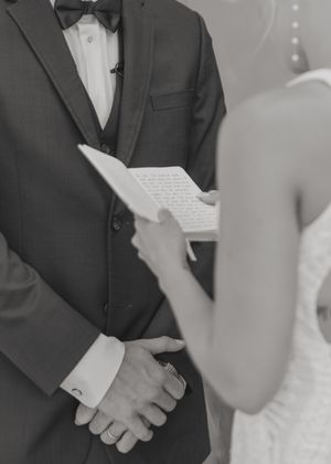 Black and white close-up of couple exchanging written vows during ceremony.