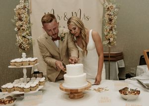 A wedding cake display with multiple tiers and desserts arranged on a table with floral decorations.