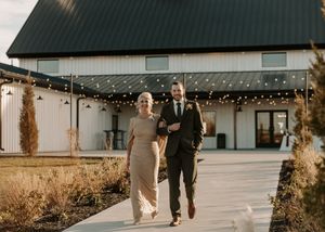 Wedding guests walking down a rustic outdoor pathway decorated with string lights and natural scenery.