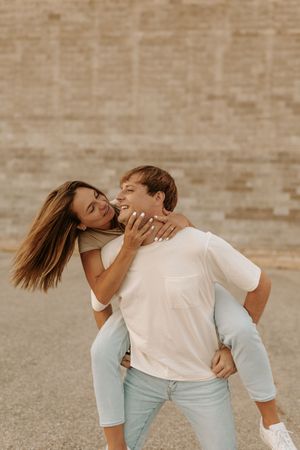 A couple shares intimate dance poses against a rustic brick wall backdrop.