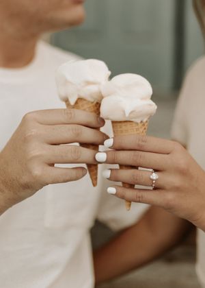Close-up of hands wearing engagement rings while holding ice cream cones.