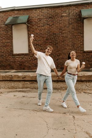 A playful sequence of two people dancing and moving along a brick building exterior.