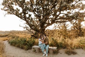 A romantic couple sits together on a rocky cliff edge during golden hour sunset at Vasquez Rocks Natural Area Park.