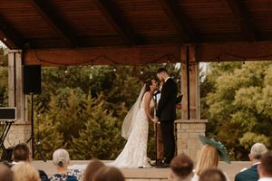A wedding couple and their guests dance and celebrate at an outdoor rustic barn reception venue.