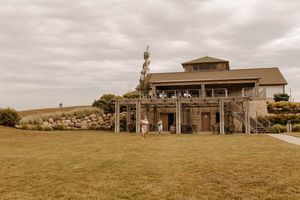 Panoramic view of a rustic event venue with rolling hills and golden fields in the background.