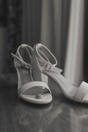 A series of white wedding sandals arranged in a row on a dark wooden floor with soft focus effect.