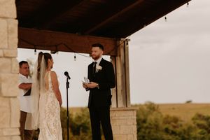 A romantic outdoor wedding ceremony setup with stone pillars and rustic decor in a natural landscape.