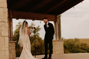 Stone pillars frame an elegant outdoor wedding venue with natural scenery in the background.