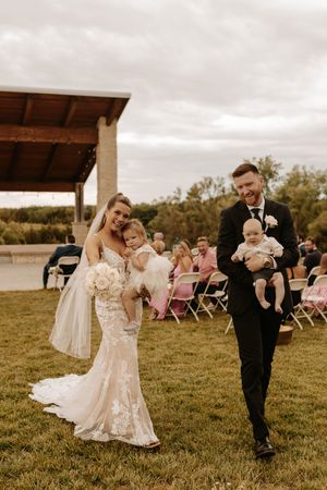 A couple dances together in an outdoor field wedding venue with pink chairs and natural scenery in the background.