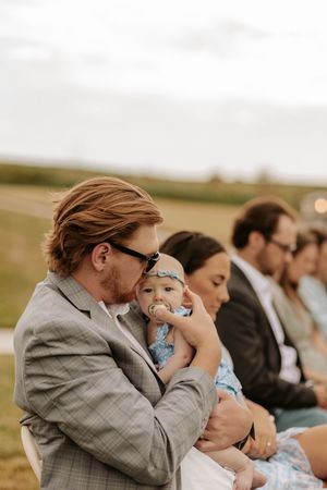 Wedding party members take synchronized sips from water bottles in an outdoor setting at sunset.