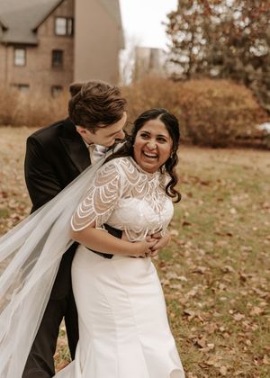 A couple shares a joyful moment together during their autumn wedding photoshoot on fallen leaves.