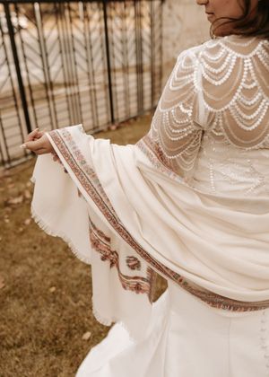 Close-up details of a white lace wedding dress with delicate pearl embellishments and intricate beadwork patterns.