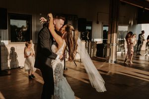 Wedding guests dance and celebrate on a dimly lit indoor dance floor during an evening reception.